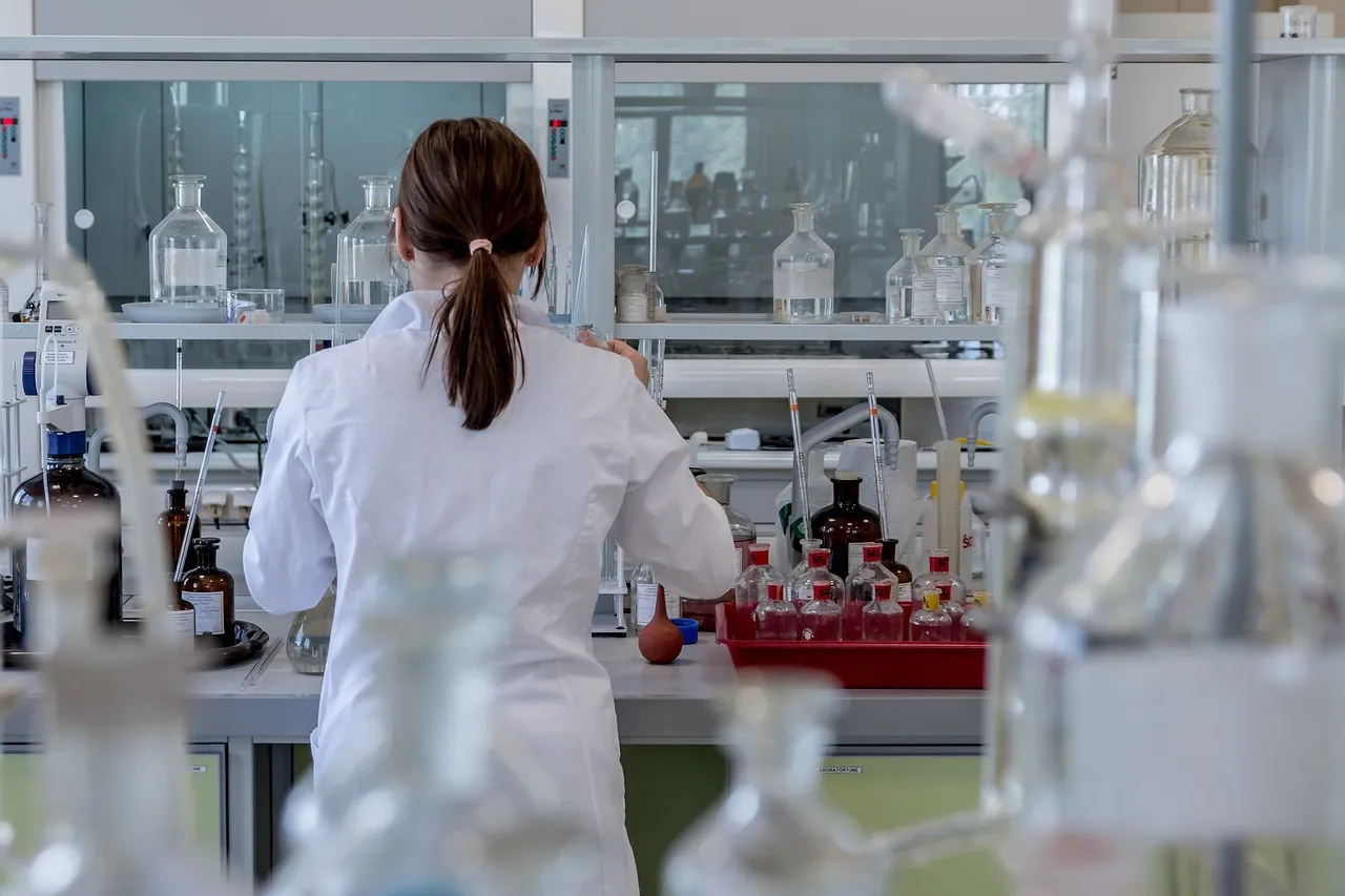Tutkija valkoisessa laboratoriotakissa työskentelee laboratoriossa lasiastioiden äärellä