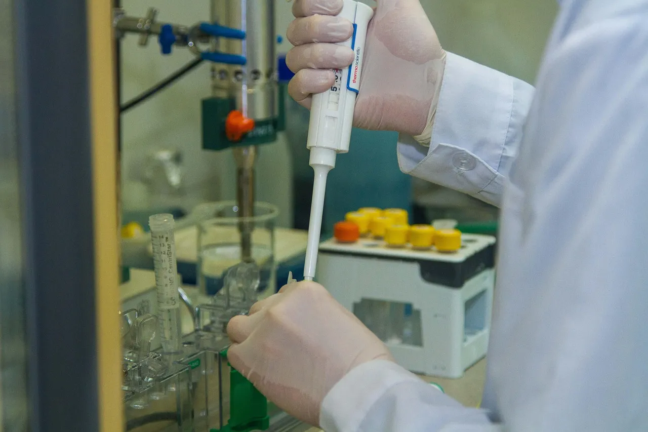 Tutkija annostelee pipetillä näytettä laboratoriossa suojakäsineet kädessään